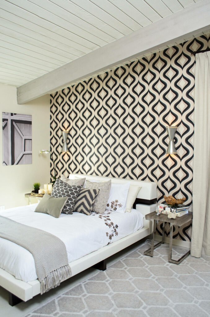 Modern bedroom featuring black and white geometric wallpaper, white bedding, and coordinating hexagon area rug