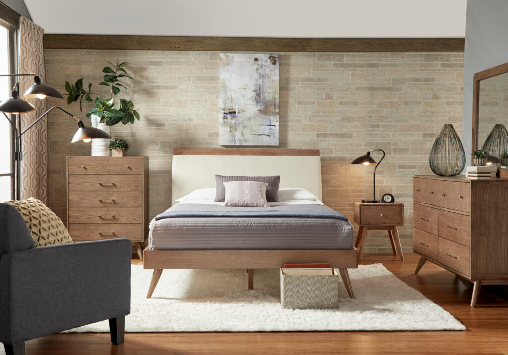 Modern bedroom featuring light wood furniture, exposed brick walls, industrial lighting, and minimalist decor